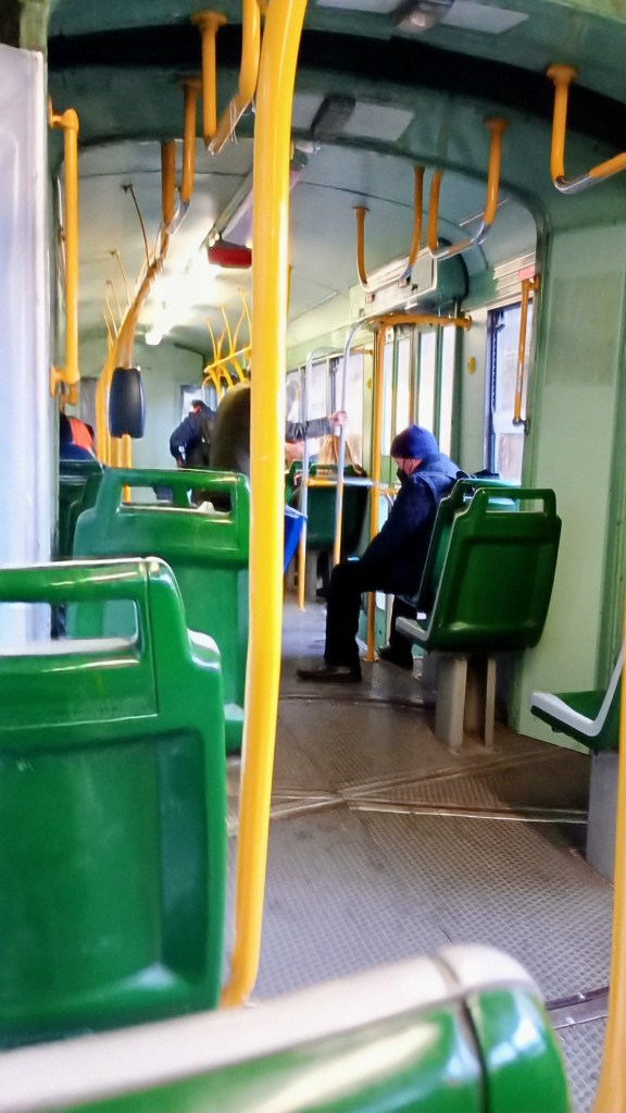 The green interior of a Roman tram with few people 