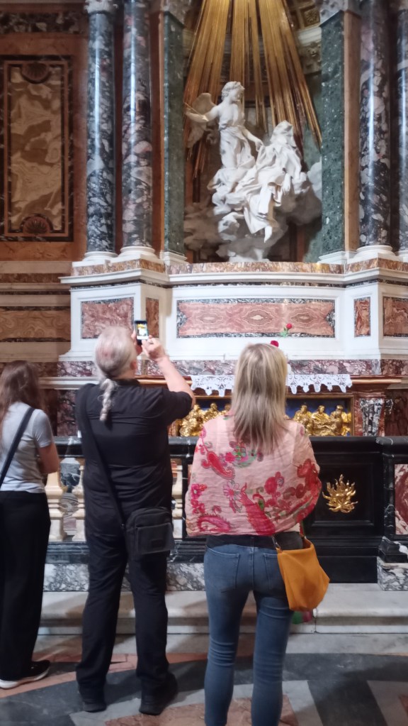 People standing in front of and photographing Bernini's St Theresa in Ecstasy 