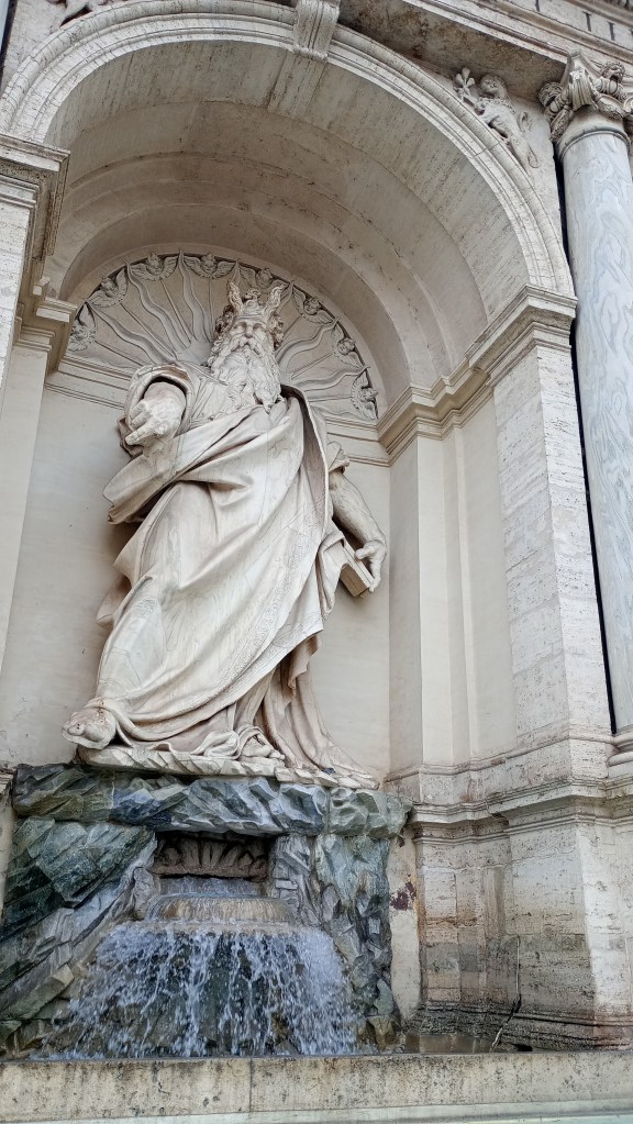 Statue of Moses with horns at a water fountain. He is pointing his figure.