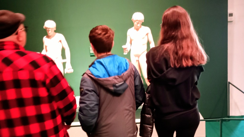 three people looking at two statues