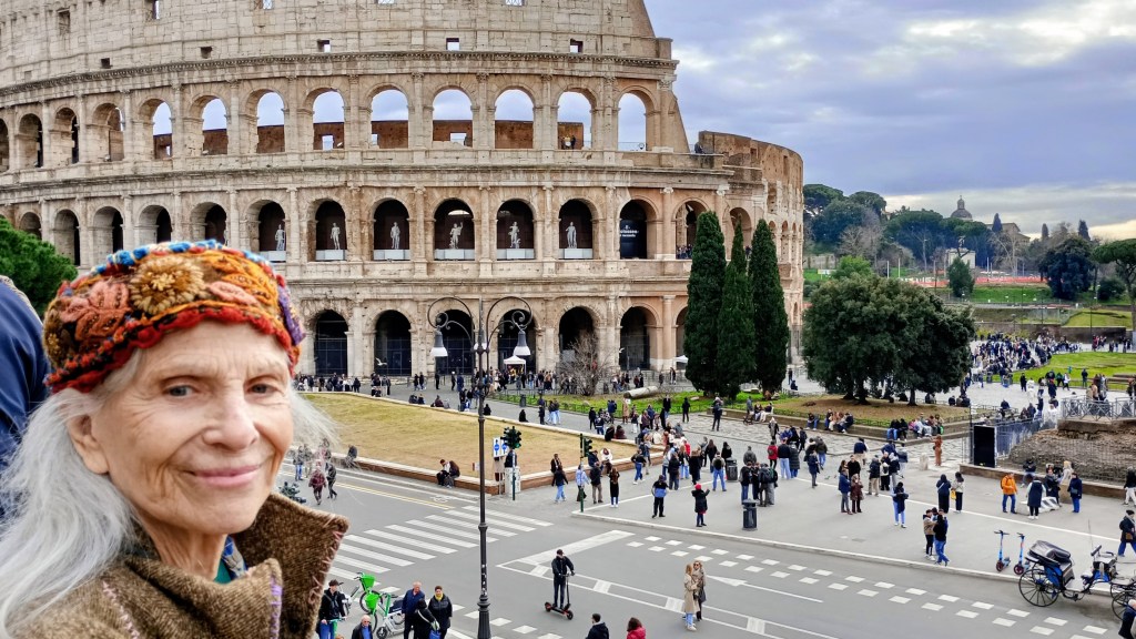 woman wearing a hat in front of the colosseum