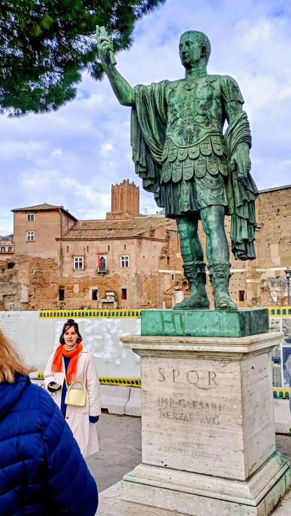 big statue of  Nerva in front of the foro. a woman is standing next to the statue