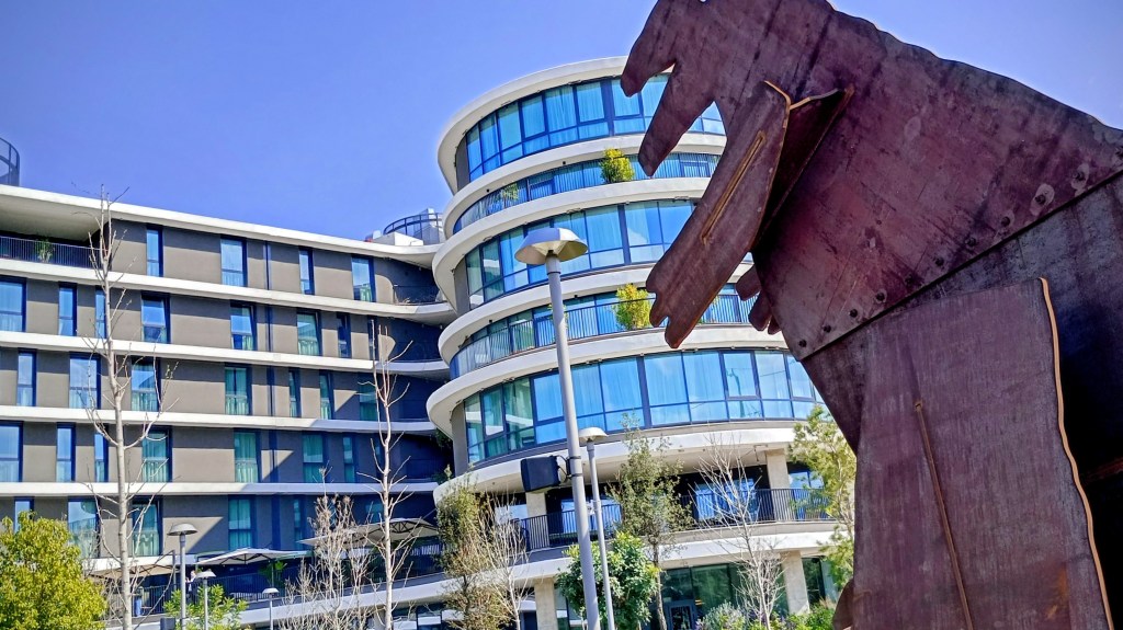 photo of a building with a metal dinosaur standing near it